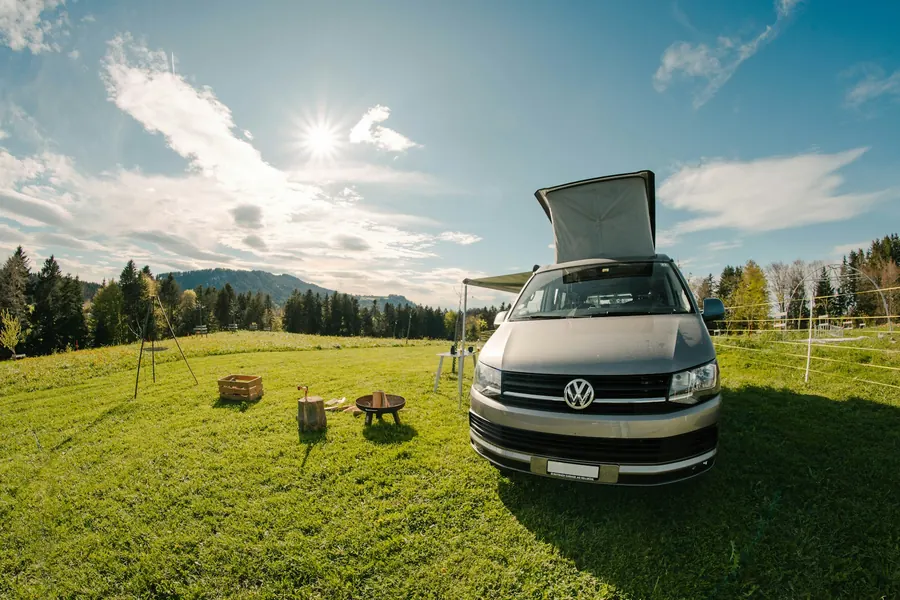 Camping-car garé sur une pelouse ensoleillée, table de pique-nique à côté