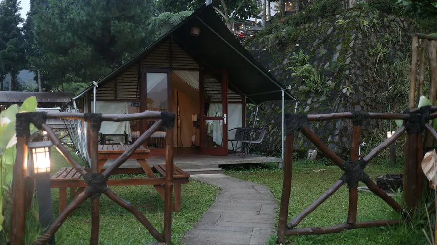 Tente de glamping en bois avec auvent ouvert sur une terrasse