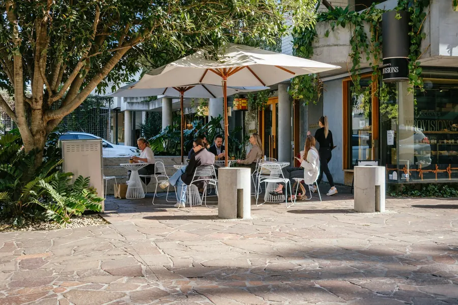 Terrasse de café ombragée avec quelques clients l'après-midi