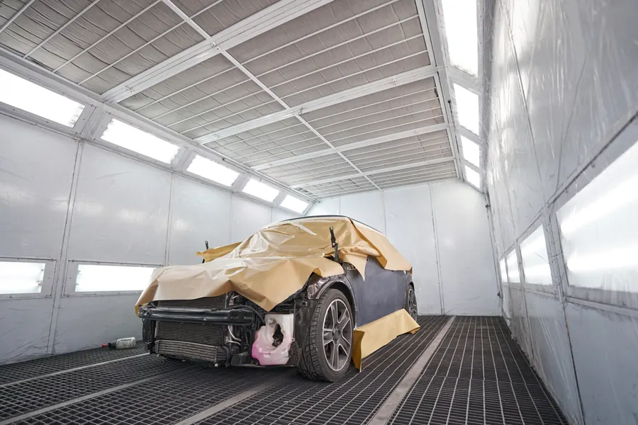Voiture masquée prête pour la peinture dans une cabine éclairée