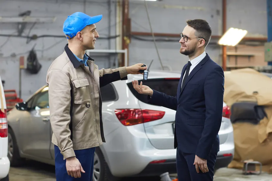 Remise des clés devant une voiture fraîchement réparée