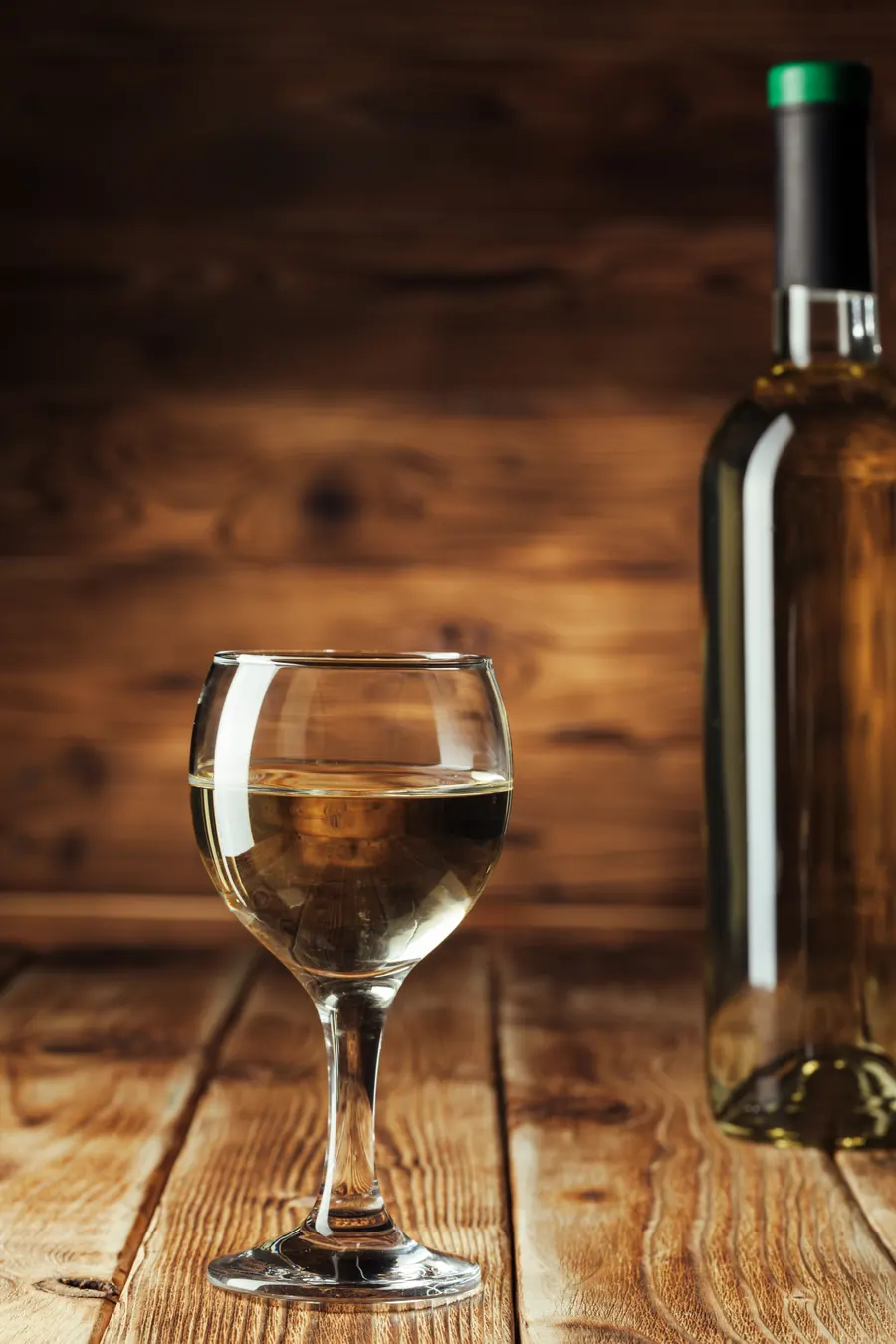Bouteille de vin blanc et verre servi sur le comptoir en bois d'une cave
