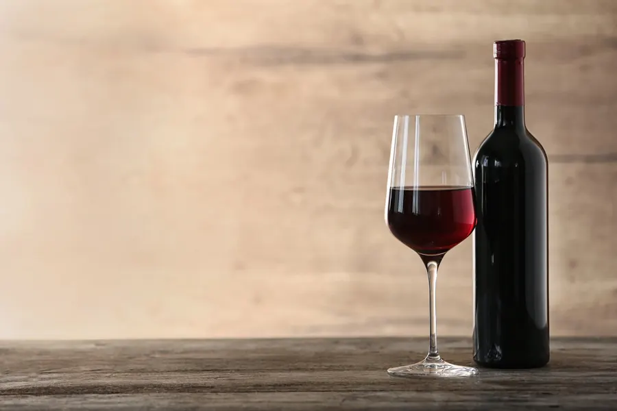 Bouteille de vin rouge et verre sur une table en chêne, lumière douce