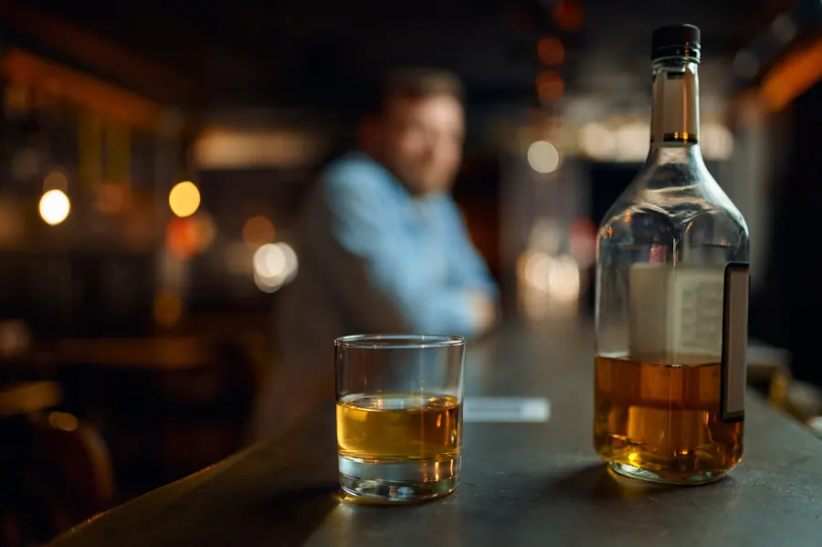 Verre de whisky et bouteille sur un comptoir en bois