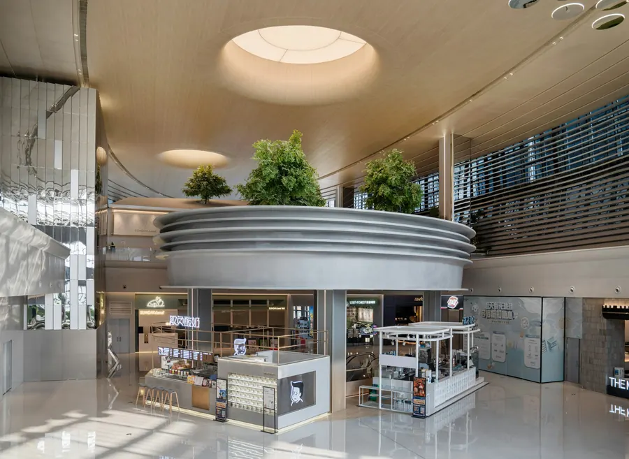 Atrium de centre commercial lumineux sous un puits de jour, kiosques et plantes