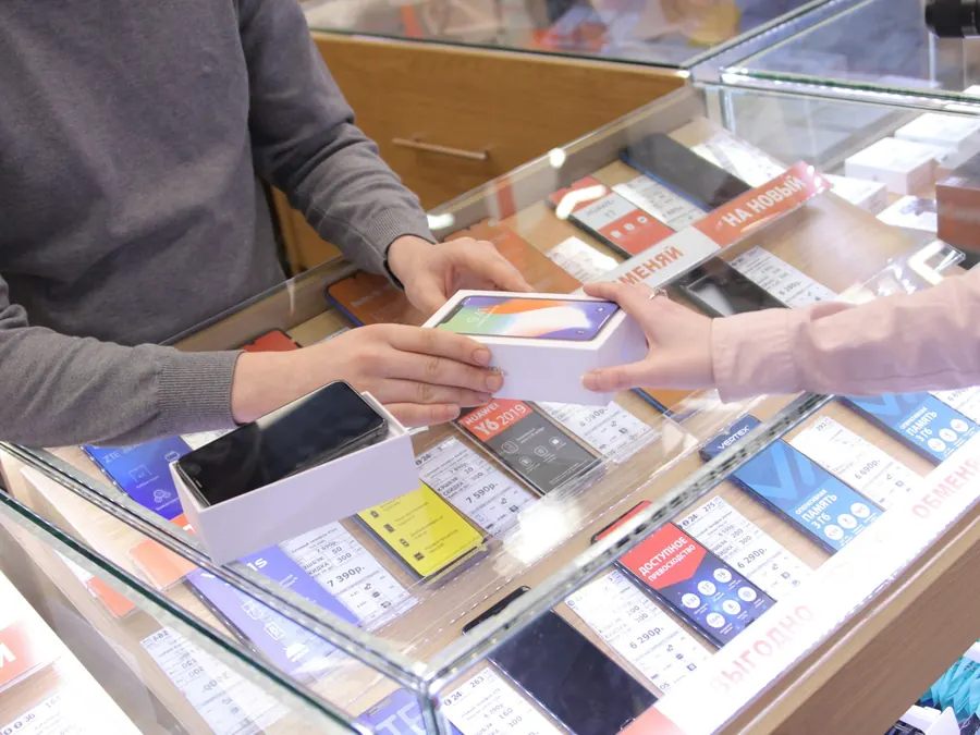 Technicien qui répare un téléphone au comptoir d'une petite boutique de galerie