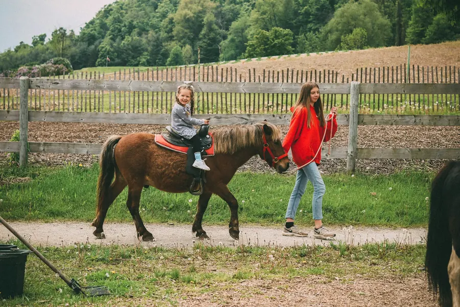 Fillette sur un poney mené à pied par un adulte