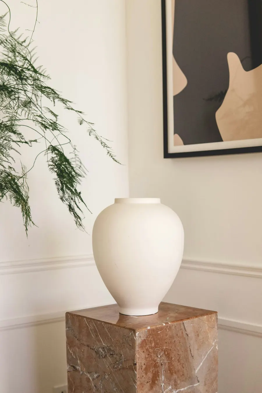 Vase en céramique blanc cassé sur un mur clair