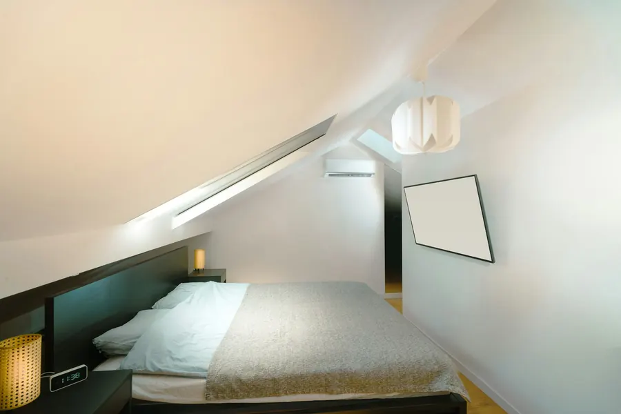Chambre mansardée avec lit blanc sous plafond incliné