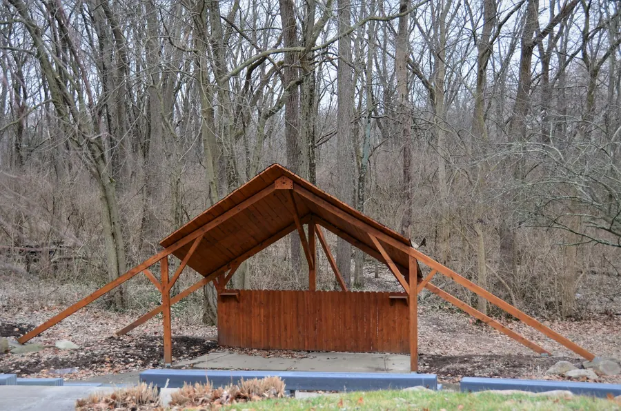 Préau ou carport en bois neuf, poteaux et assemblages visibles, jardin