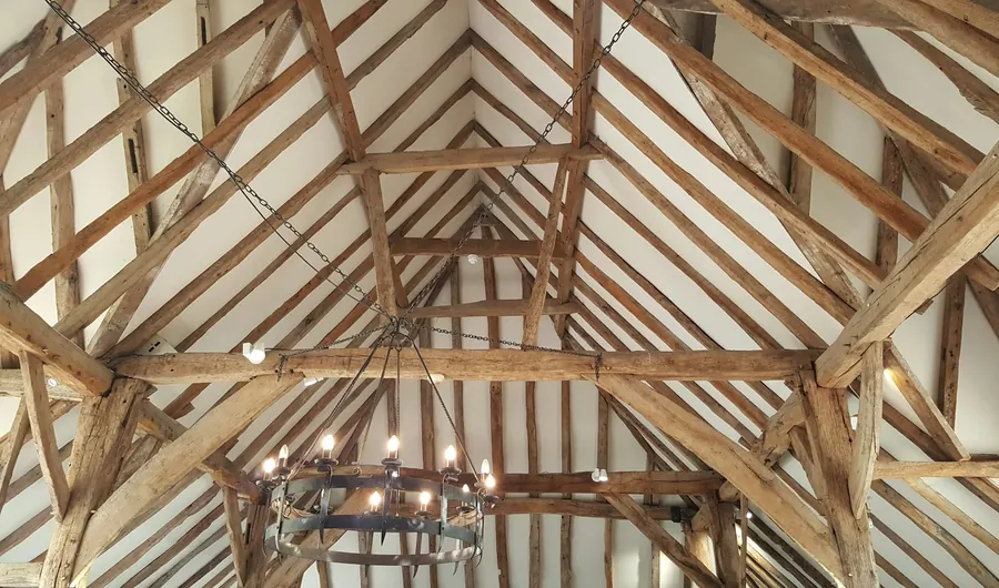 Intérieur d'une grange, charpente ancienne restaurée avec quelques pièces neuves plus claires