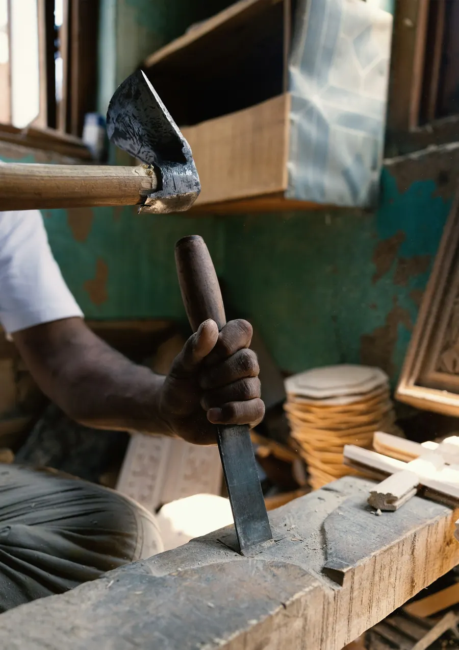 Charpentier d'une quarantaine d'années dans son atelier, ciseau à bois à la main, lumière latérale
