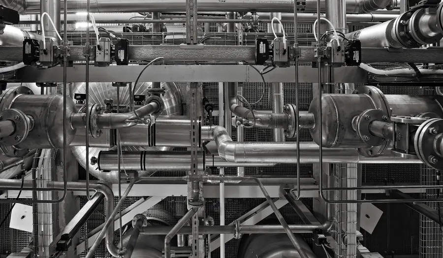Réseau de tubes inox soudés dans une usine alimentaire, colliers et vannes, sans marque visible