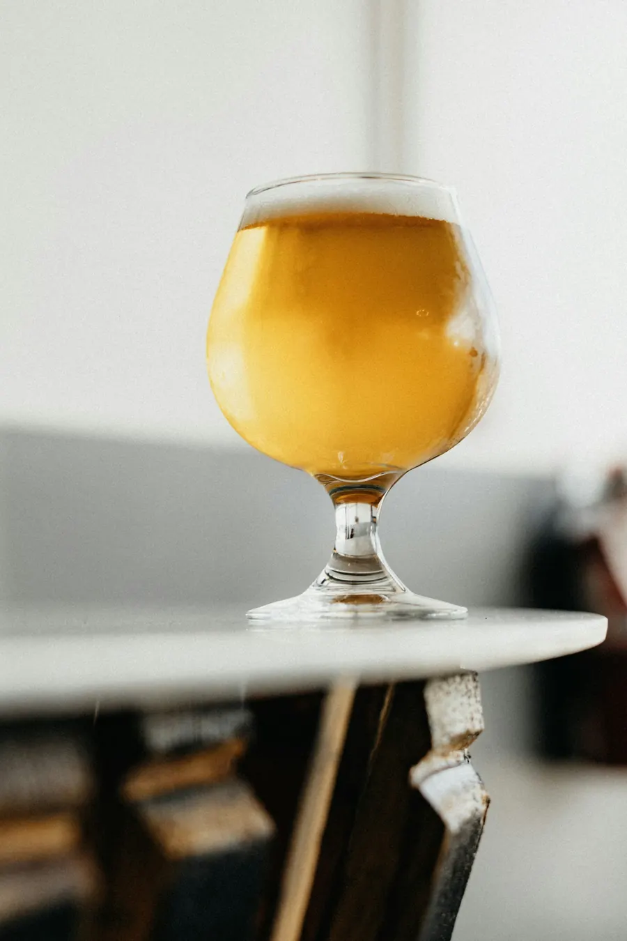 Verre à pied avec une boisson dorée mousseuse, sans bouteille