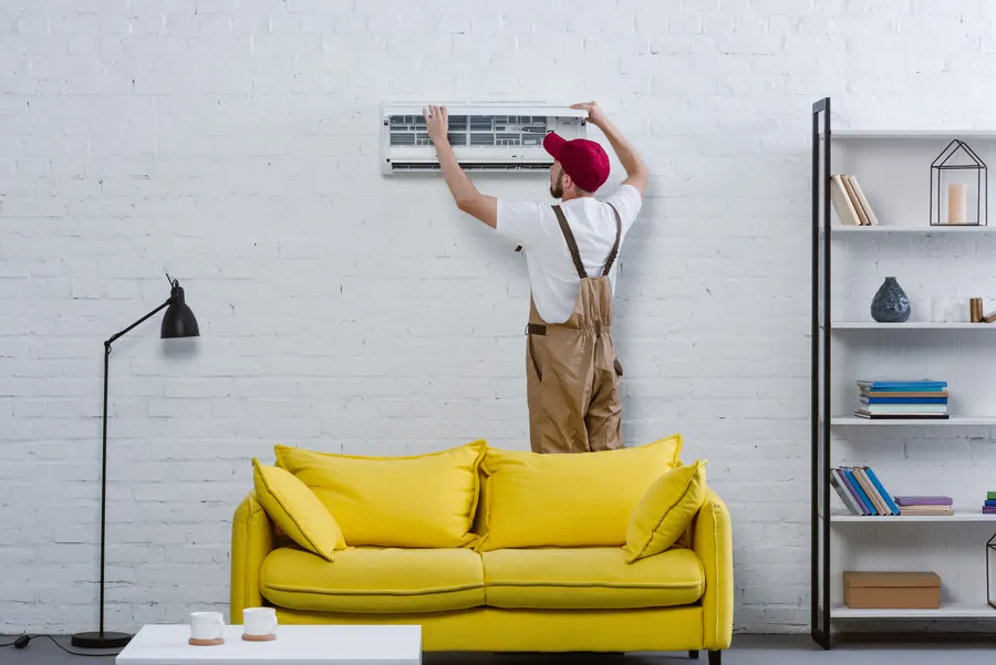 Technicien sur un escabeau posant une unité murale blanche, séjour lumineux