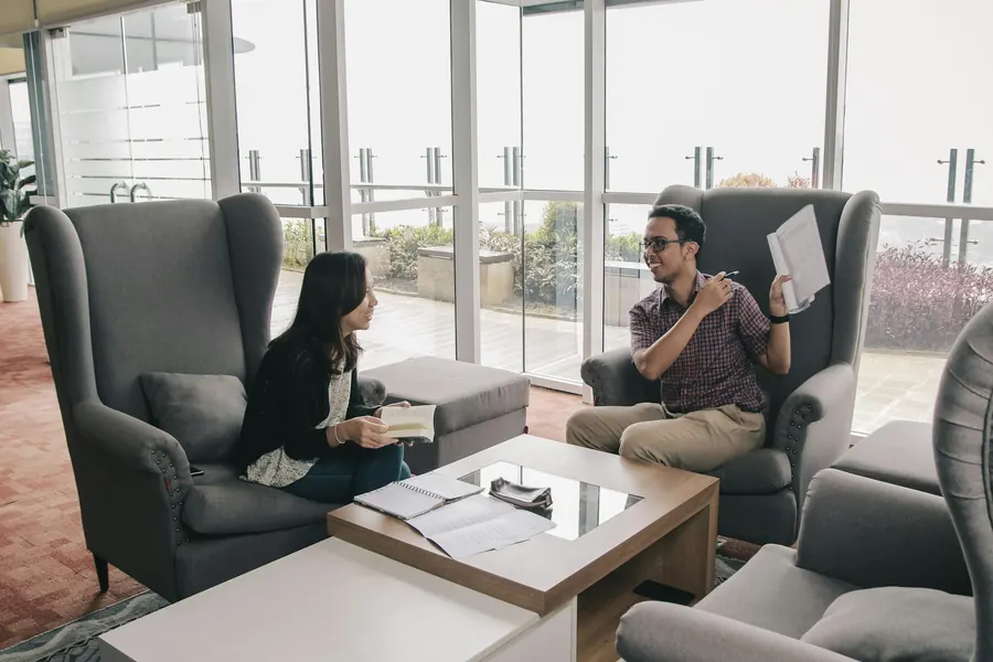 Séance de coaching, deux fauteuils face à face, carnet ouvert