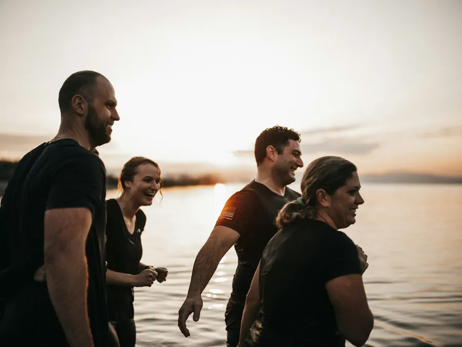 Petit groupe d'adultes actifs près de l'eau au coucher du soleil