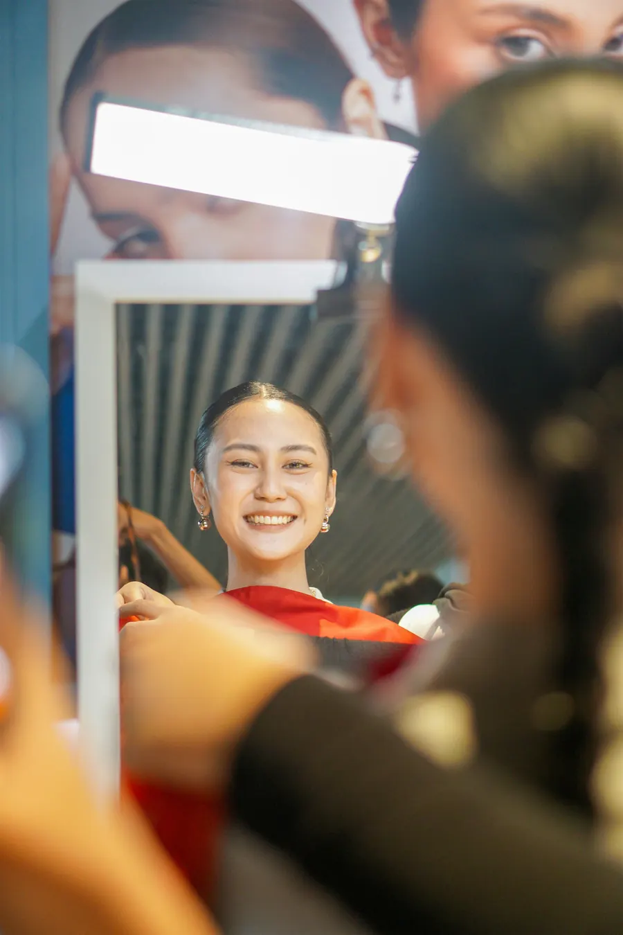 Jeune coiffeuse souriante devant un miroir, lumière de vitrine