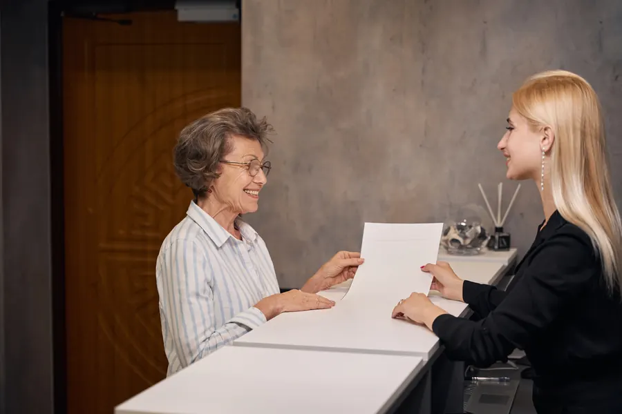Accueil d'une étude, une collaboratrice explique un document à un visiteur, ambiance calme