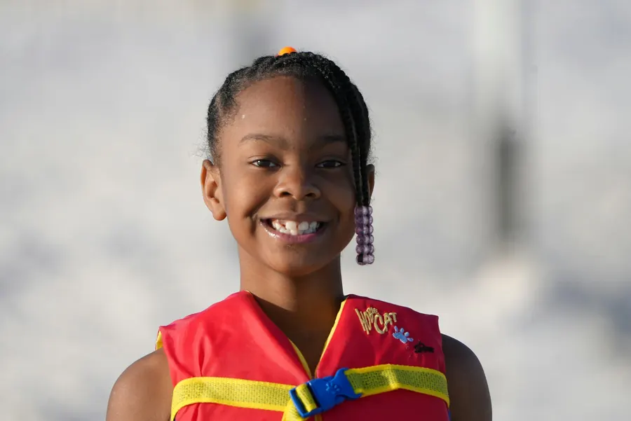 Jeune fille souriante portant un gilet de sauvetage, en extérieur