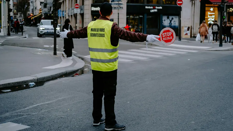 Bénévole vu de dos qui dirige la circulation avec un panneau stop