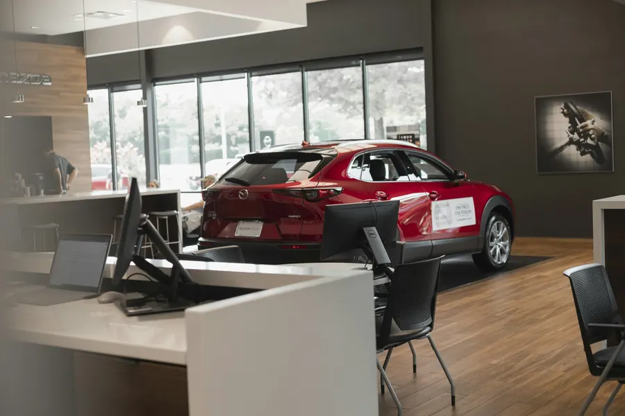 Voiture rouge exposée dans un showroom lumineux, bureau de vente au premier plan