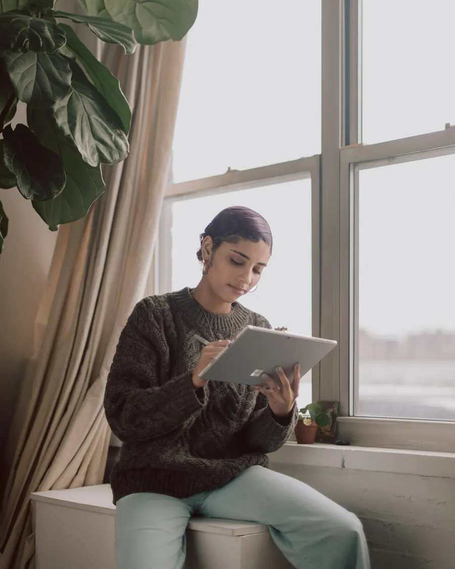 Femme avec une tablette près d'une fenêtre, dans une pièce