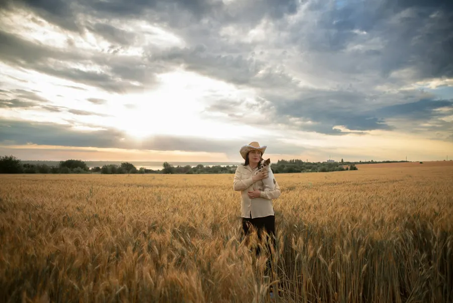 Femme debout seule dans un champ de blé, ciel nuageux