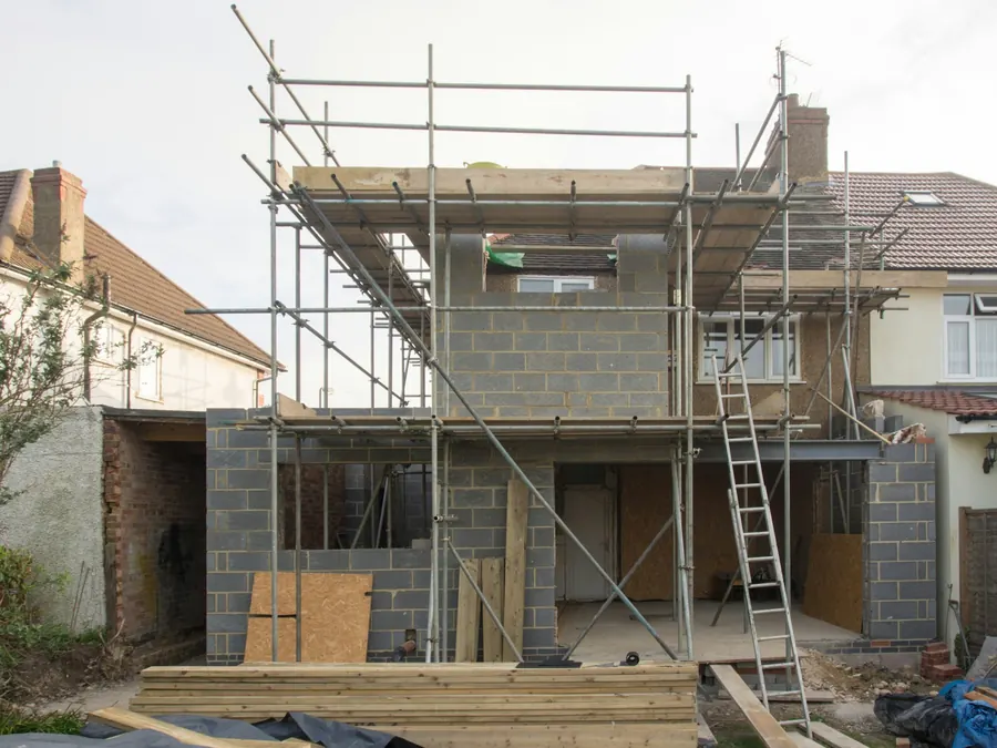 Extension de maison en parpaings avec échafaudage, chantier en cours