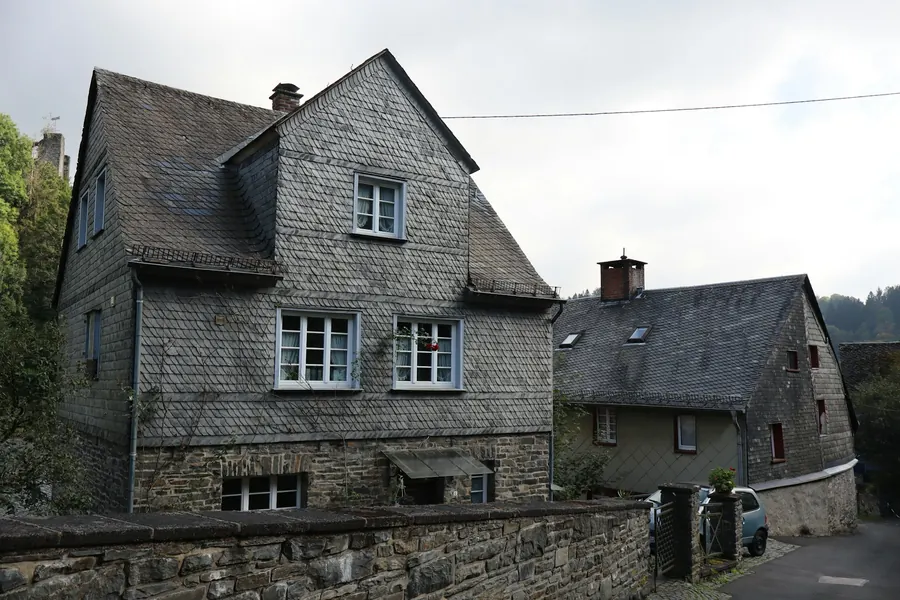 Maison ancienne en pierre grise dans un village, toiture en ardoise