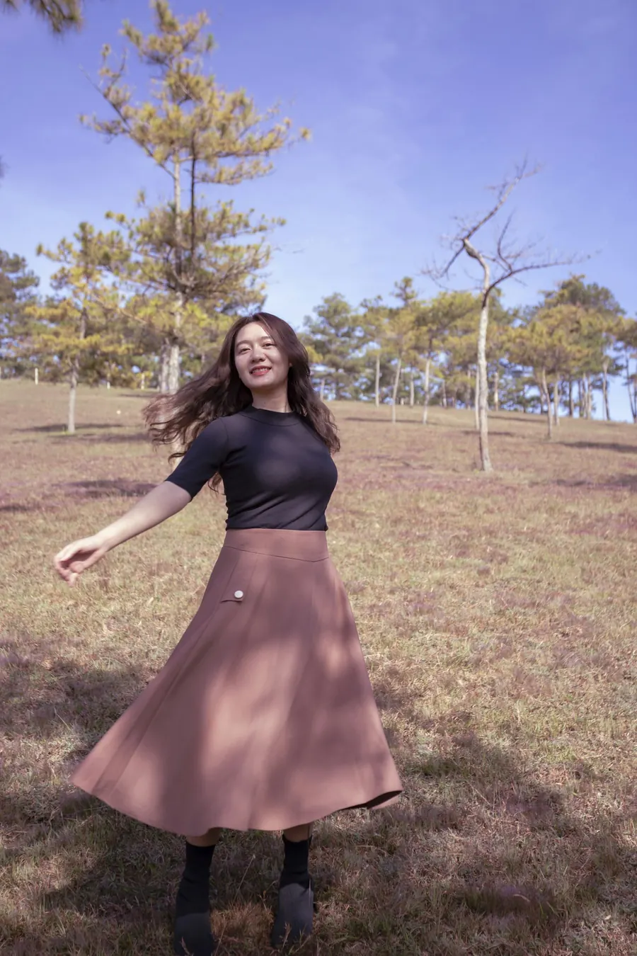Femme qui tourne dans un champ, jupe mauve en mouvement