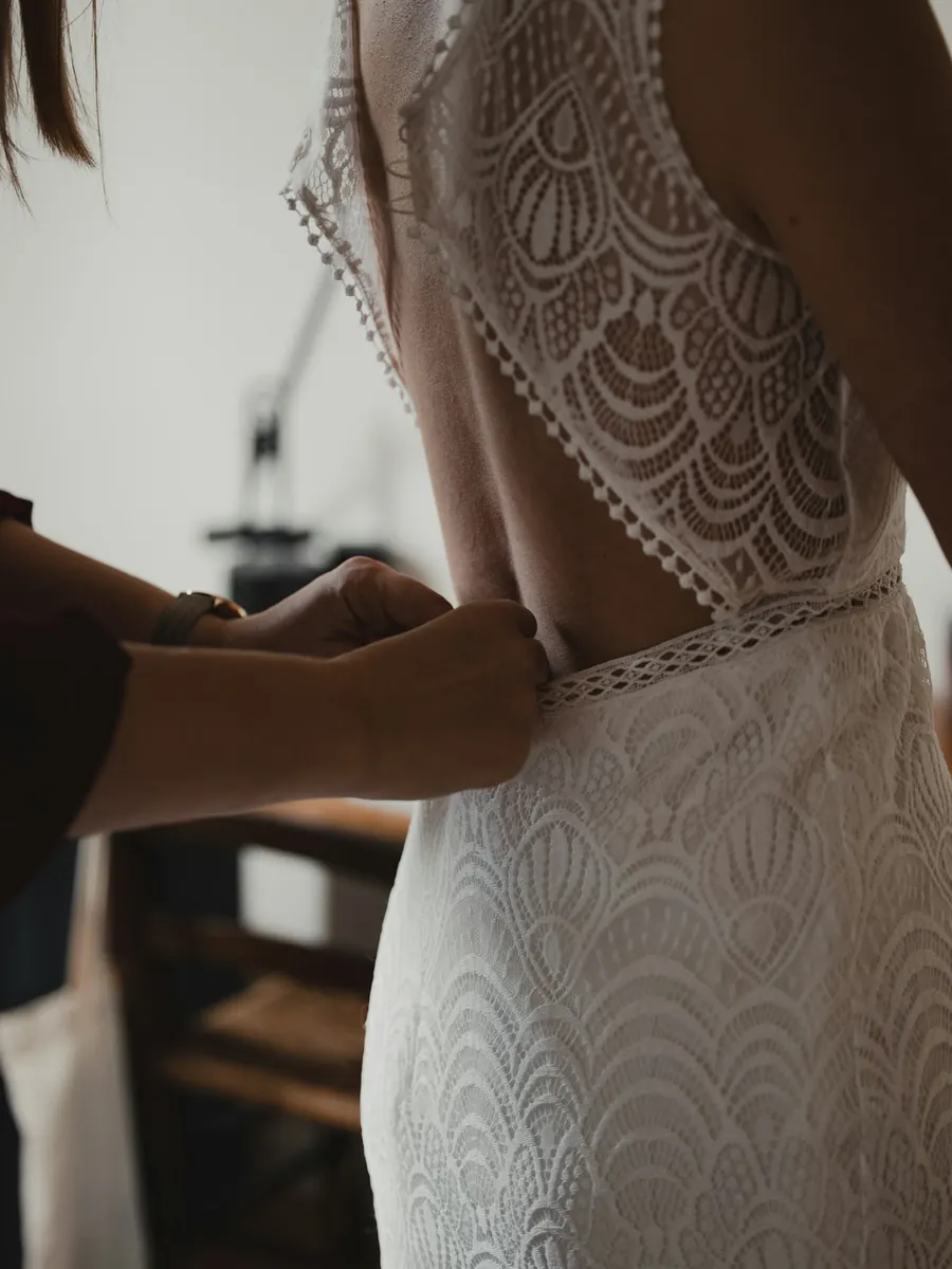 Mains qui ajustent le dos d'une robe en dentelle sur une cliente