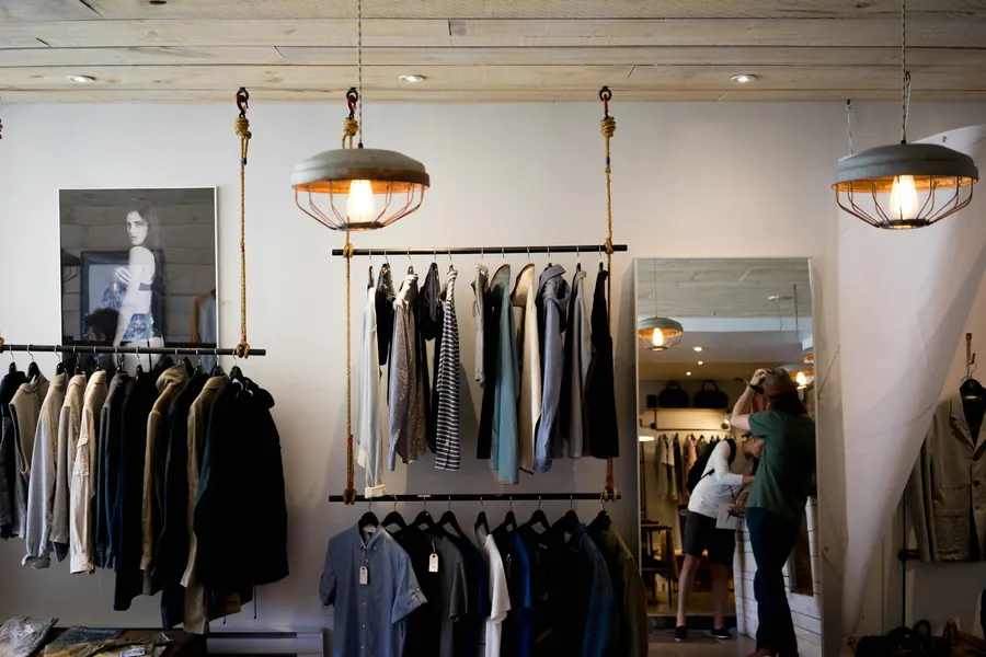 Intérieur de boutique avec portants de vêtements et cliente