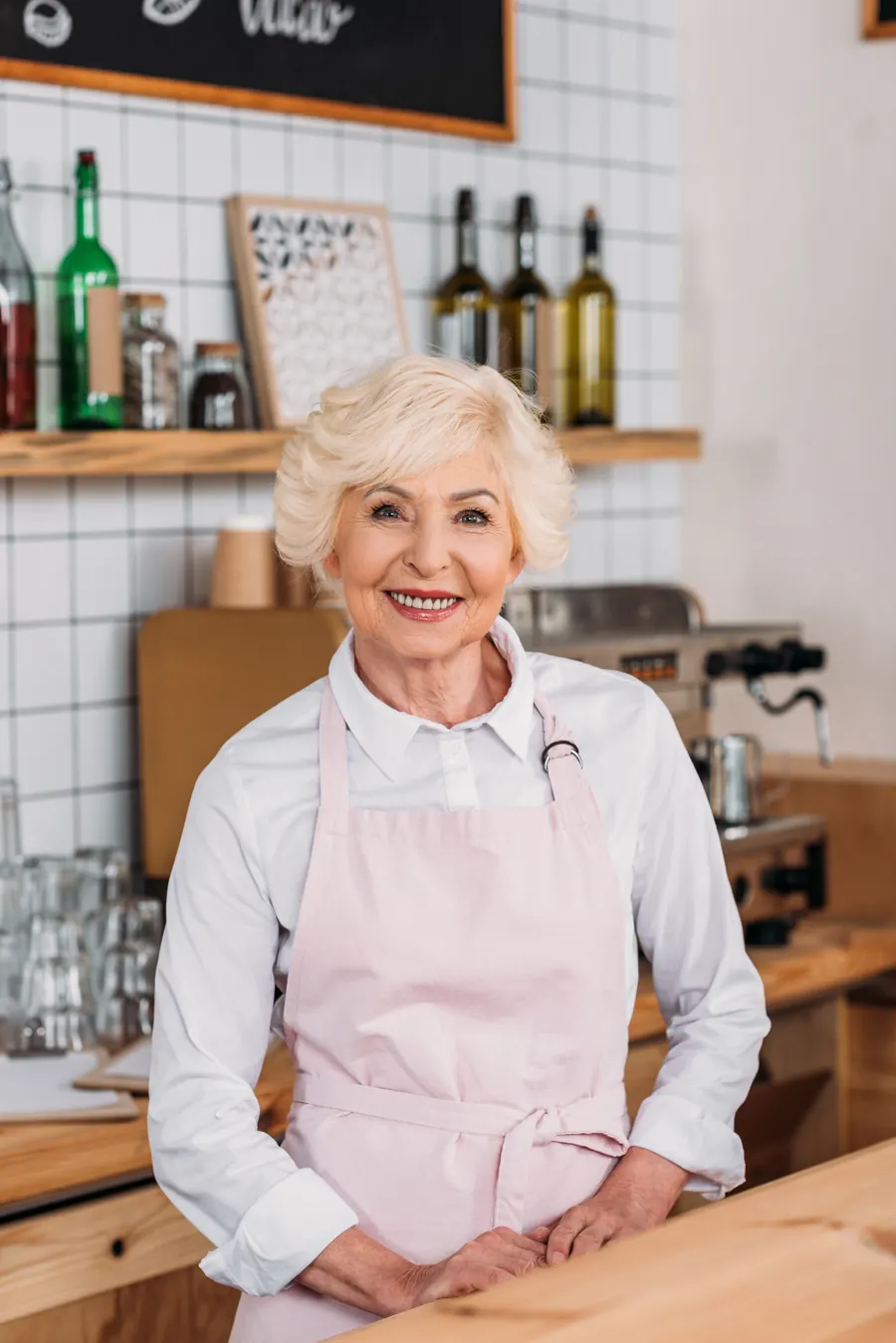 Femme de 75 ans souriante, tablier, dans une petite cuisine de crêperie
