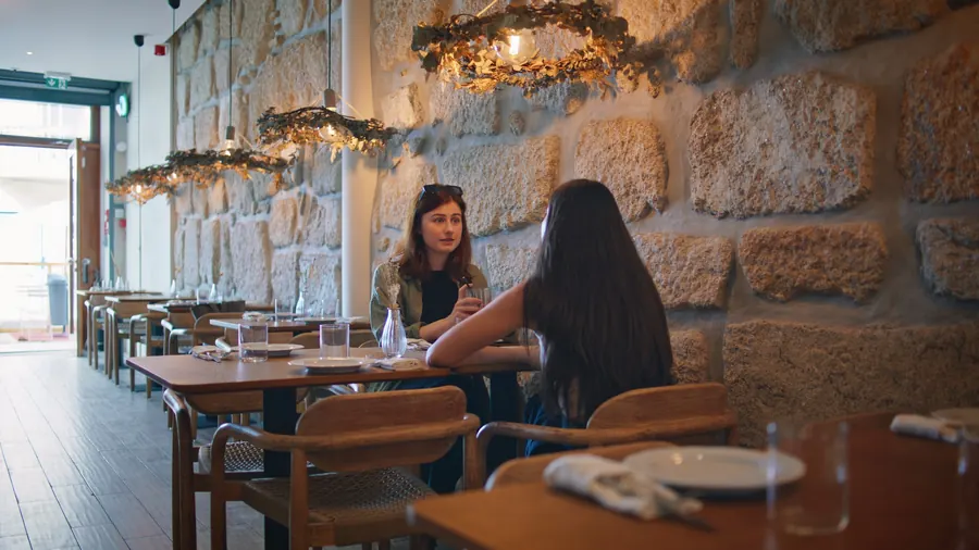 Salle de crêperie aux murs de pierre, tables en bois, nappes à carreaux discrètes
