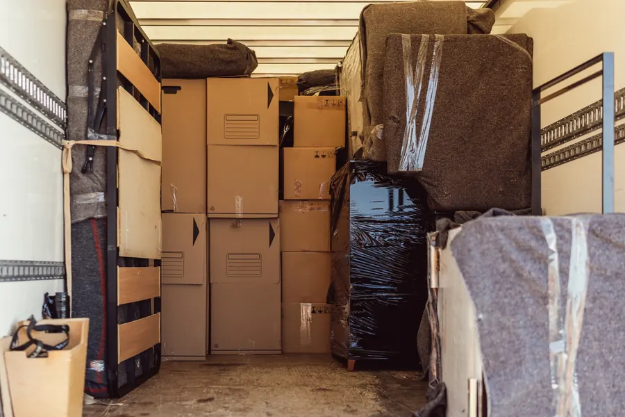 Intérieur d'un camion de déménagement chargé, meubles sous couvertures et sangles