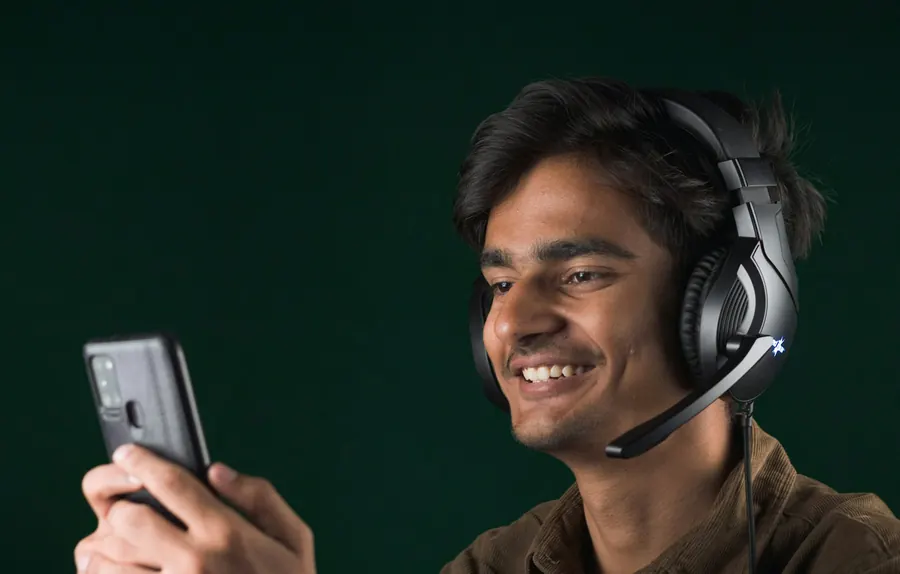 Un homme souriant portant un casque avec micro, fond uni