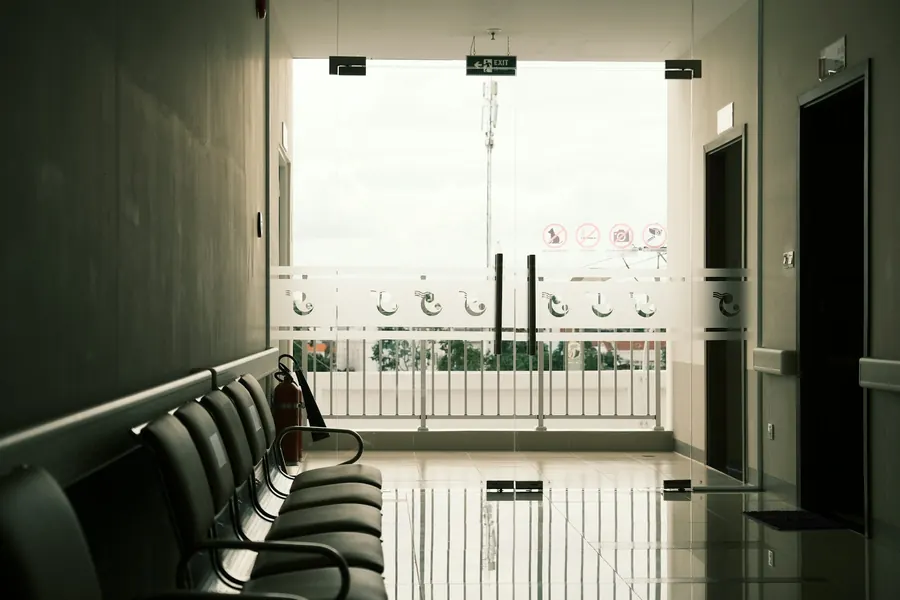Salle d'attente blanche et épurée, chaises alignées, lumière naturelle, personne