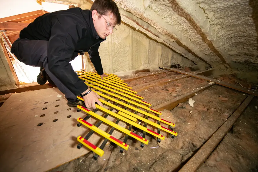 Inspection des combles à la lampe, laine isolante et charpente