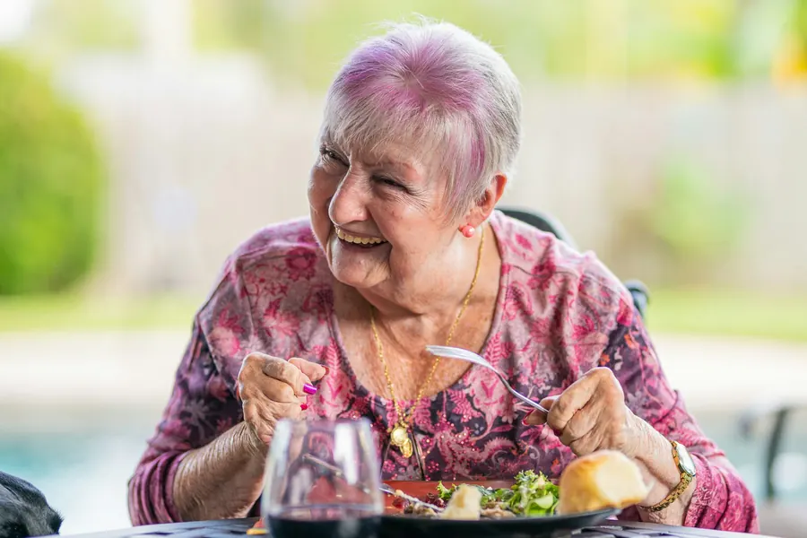 Femme âgée souriante qui déjeune seule en extérieur