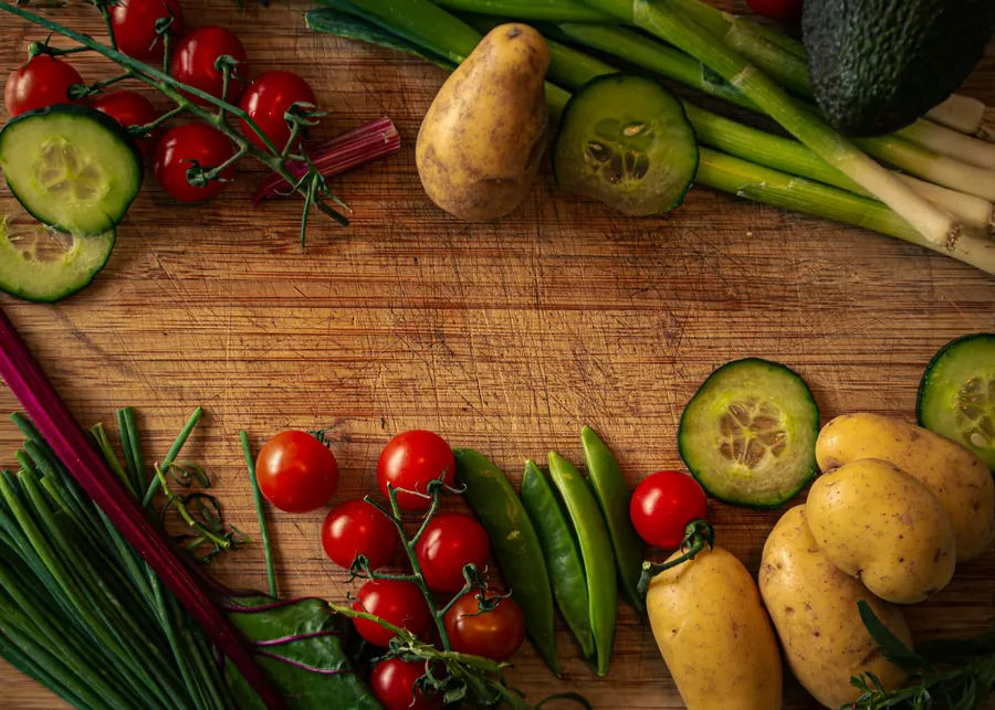 Légumes frais disposés autour d'une planche en bois, tomates, concombre et pommes de terre