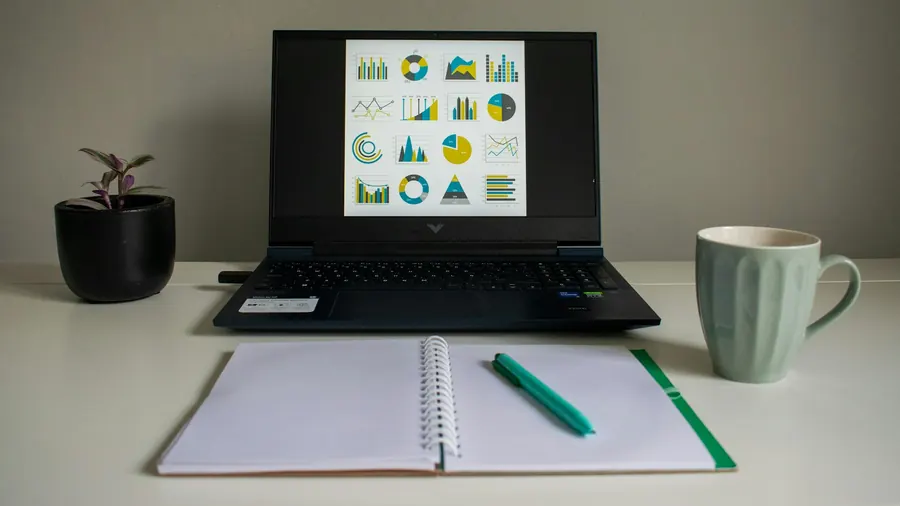 Ordinateur portable ouvert pour une visio, carnet et tasse, bureau à la maison