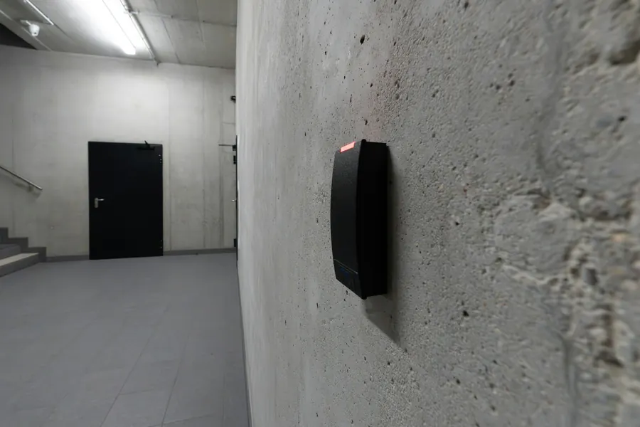 Lecteur de badge sur un mur près d'une porte sombre, couloir lumineux