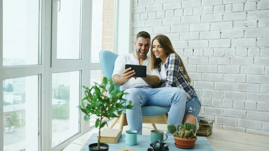 Couple joyeux qui regarde une tablette ensemble dans leur salon
