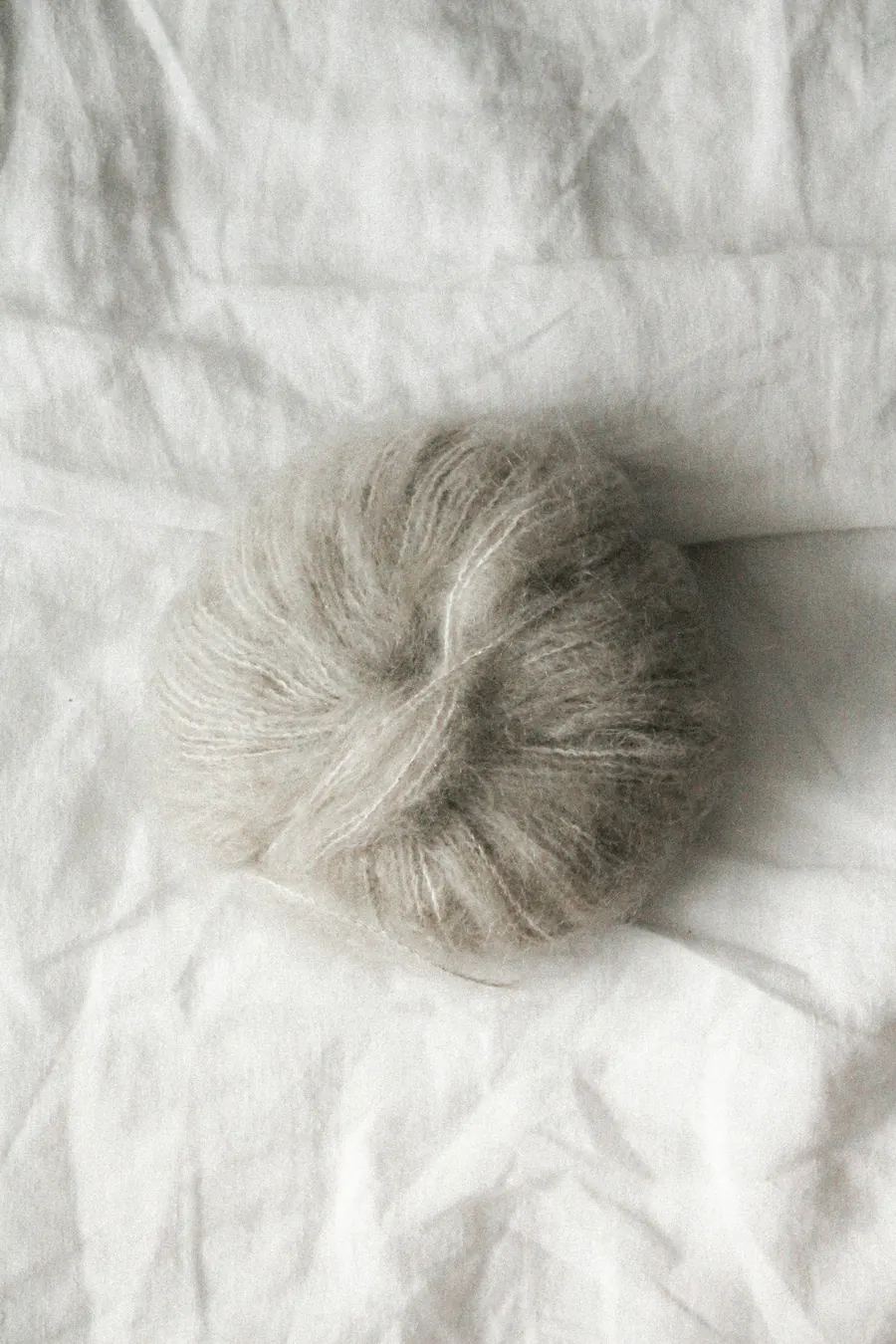 Pelote de mohair et soie grise très aérienne, fond crème