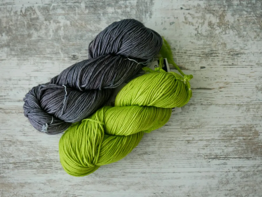Écheveau de mérinos vert pomme, légères variations de teinte, sur bois clair