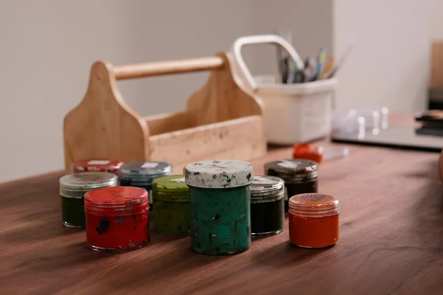 Petits pots de peinture colorés alignés sur une table en bois