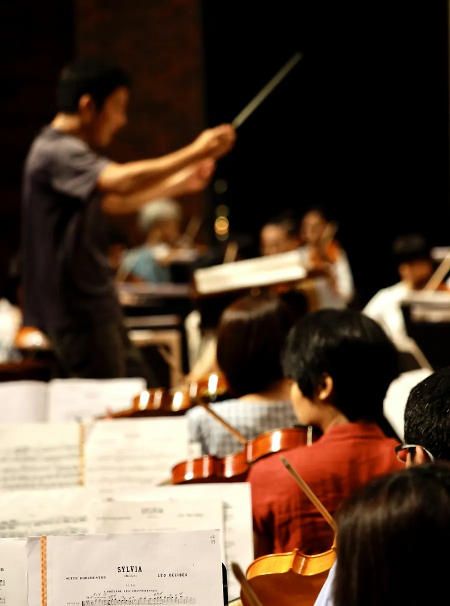 Orchestre d'enfants de 10 à 14 ans en répétition, violons et violoncelles, pupitres, salle simple