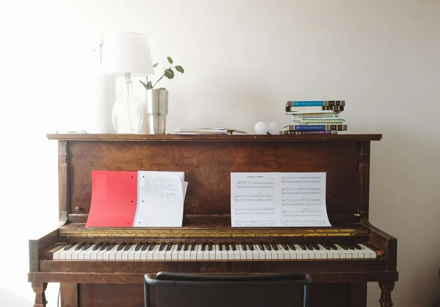 Piano droit brun dans une pièce éclairée par une fenêtre
