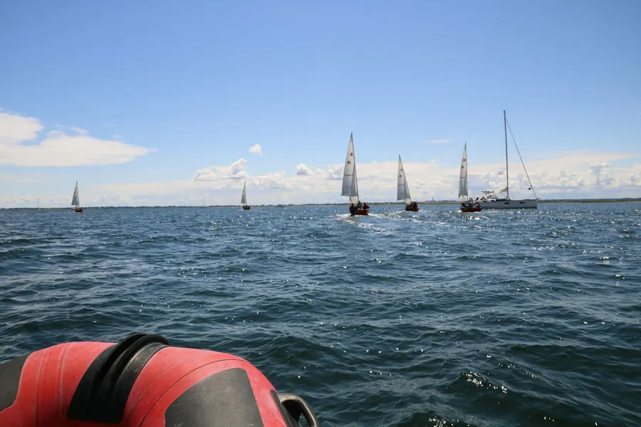 Vue depuis un bateau pneumatique rouge vers un groupe de voiliers au loin